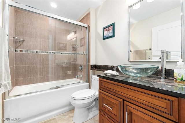 bathroom featuring toilet, tile patterned flooring, bath / shower combo with glass door, and vanity