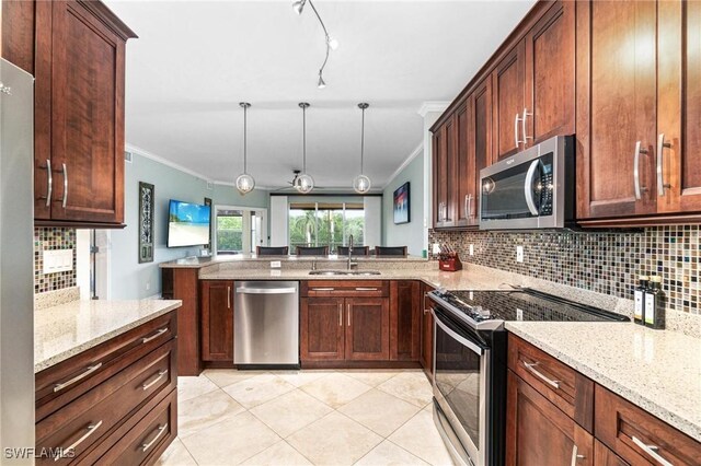 kitchen featuring appliances with stainless steel finishes, decorative light fixtures, a peninsula, crown molding, and a sink