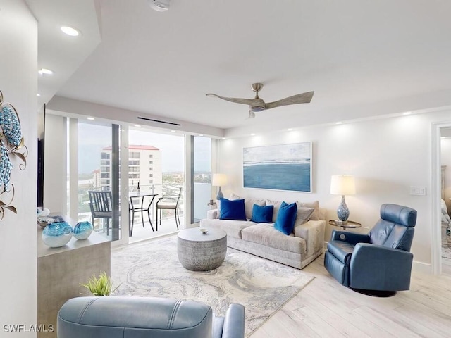 living room featuring light wood-type flooring, ceiling fan, and floor to ceiling windows