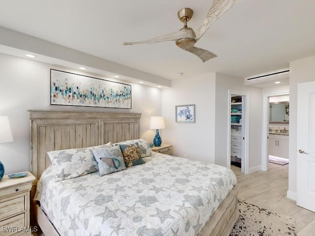 bedroom featuring ceiling fan, ensuite bath, a closet, a walk in closet, and light hardwood / wood-style flooring