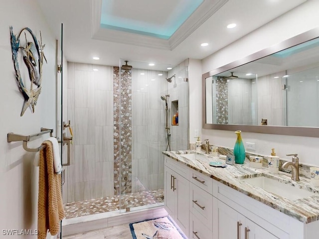 bathroom with a tray ceiling, tiled shower, and vanity