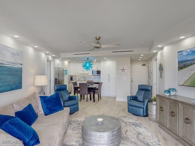 living room with ceiling fan, sink, and light wood-type flooring