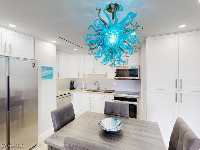 kitchen with sink, backsplash, white cabinets, and stainless steel appliances