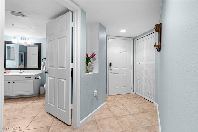 hall featuring sink and light tile patterned floors