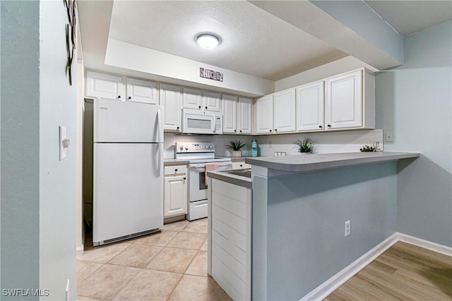 kitchen featuring white appliances, a textured ceiling, white cabinetry, light tile patterned floors, and kitchen peninsula