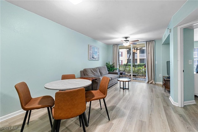 dining space with light hardwood / wood-style floors, a wall of windows, and ceiling fan