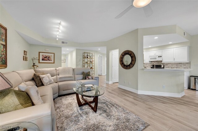 living room featuring ceiling fan, rail lighting, and light hardwood / wood-style flooring