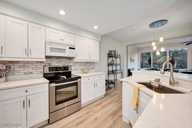 kitchen with hanging light fixtures, white cabinetry, electric range, and decorative backsplash