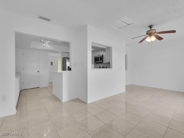 tiled spare room with ceiling fan and a textured ceiling