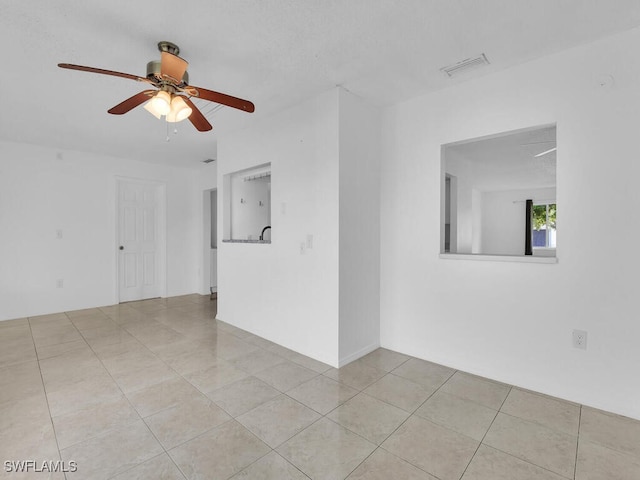 tiled spare room featuring ceiling fan