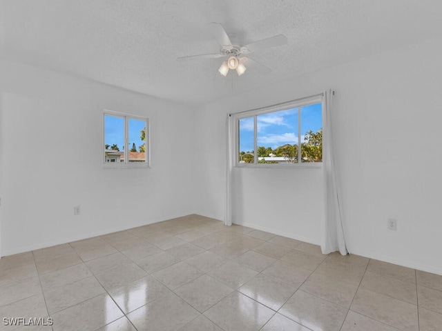 unfurnished room with ceiling fan, light tile patterned floors, and a textured ceiling