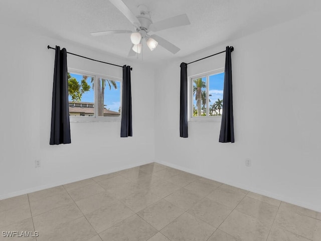 tiled empty room with a textured ceiling and ceiling fan