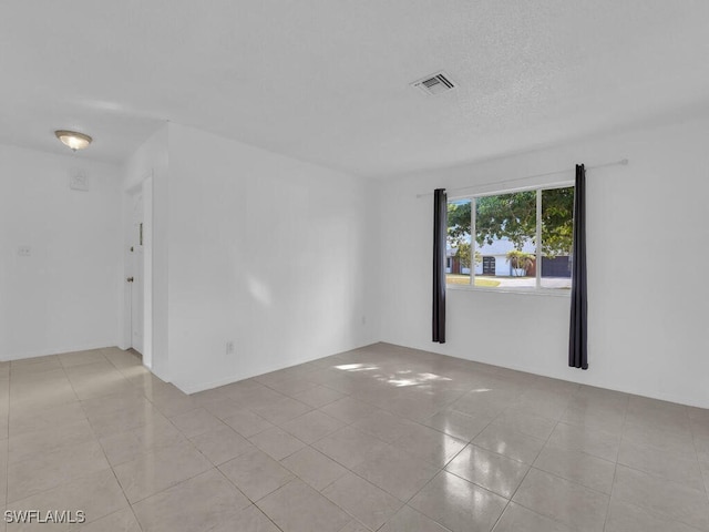 unfurnished room with light tile patterned flooring and a textured ceiling