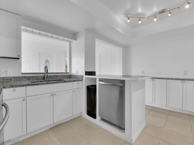 kitchen featuring kitchen peninsula, sink, white cabinets, dark stone counters, and light tile patterned floors