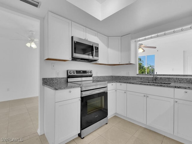 kitchen with white cabinets, appliances with stainless steel finishes, dark stone counters, sink, and ceiling fan