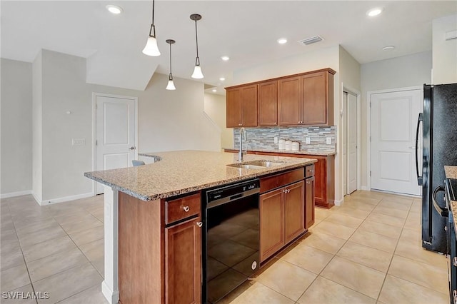 kitchen featuring black appliances, light stone countertops, sink, decorative light fixtures, and an island with sink