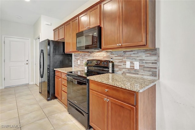 kitchen featuring light stone countertops, light tile patterned floors, decorative backsplash, and black appliances