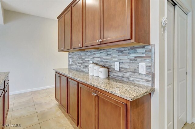 kitchen featuring decorative backsplash, light tile patterned floors, and light stone countertops