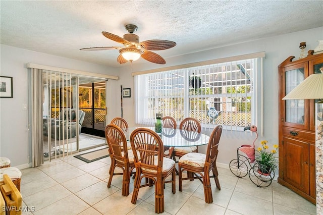 dining room featuring ceiling fan, a wealth of natural light, and light tile patterned floors