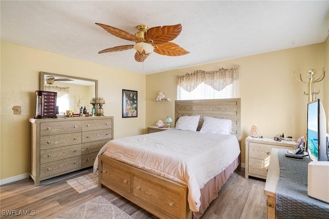 bedroom with hardwood / wood-style flooring, a textured ceiling, and ceiling fan