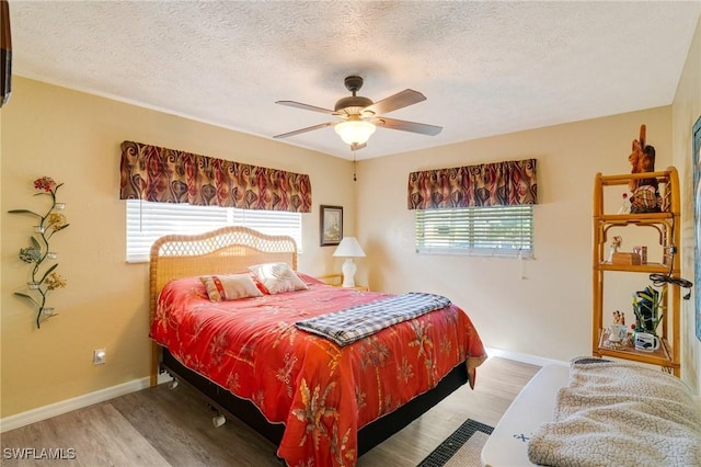 bedroom with multiple windows, a textured ceiling, ceiling fan, and light wood-type flooring