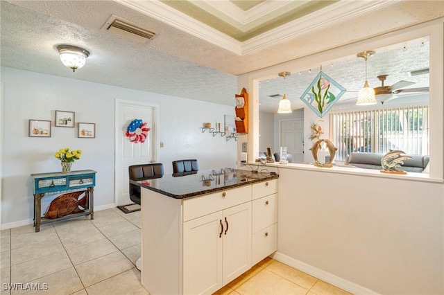 kitchen featuring kitchen peninsula, light tile patterned flooring, crown molding, and white cabinetry