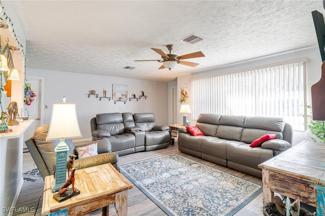 living room featuring a textured ceiling, hardwood / wood-style floors, and ceiling fan