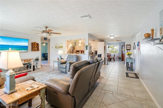 living room with ceiling fan, a textured ceiling, and light tile patterned floors