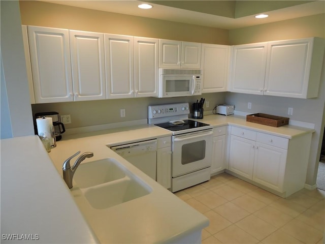 kitchen featuring white appliances, white cabinets, light tile patterned floors, and sink