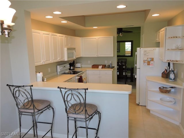 kitchen with white appliances, white cabinets, and kitchen peninsula