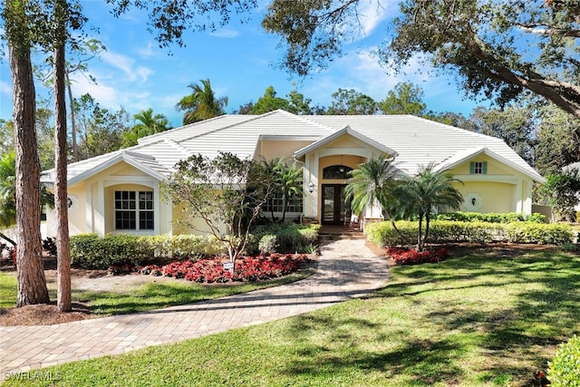 ranch-style house featuring a front yard, french doors, and stucco siding