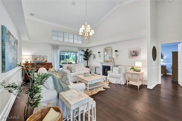 living room featuring a glass covered fireplace, hardwood / wood-style flooring, a wainscoted wall, high vaulted ceiling, and a notable chandelier