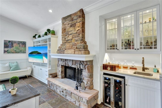 bar featuring a stone fireplace, wine cooler, a sink, ornamental molding, and wet bar