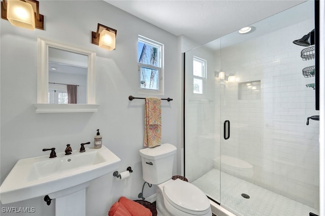 bathroom with a sink, a shower stall, and toilet