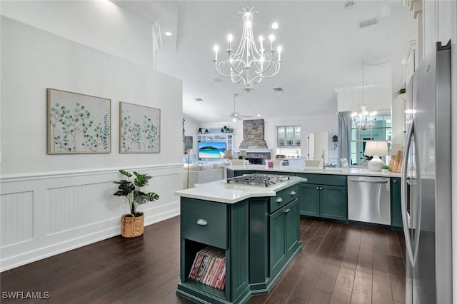 kitchen featuring open floor plan, stainless steel appliances, a fireplace, green cabinets, and ceiling fan with notable chandelier