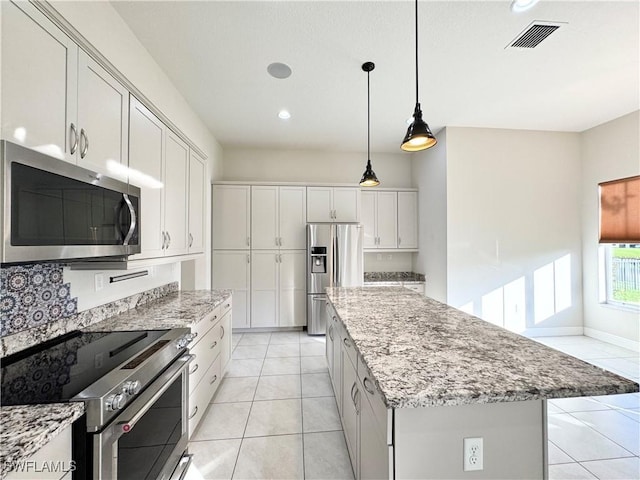 5161 Vizcaya St, Ave Maria, FL 34142 - kitchen with stainless steel appliances, a center island, light tile patterned floors, light stone countertops, and recessed lighting