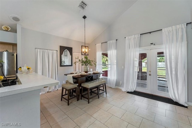 tiled dining room featuring high vaulted ceiling, a notable chandelier, french doors, and a healthy amount of sunlight