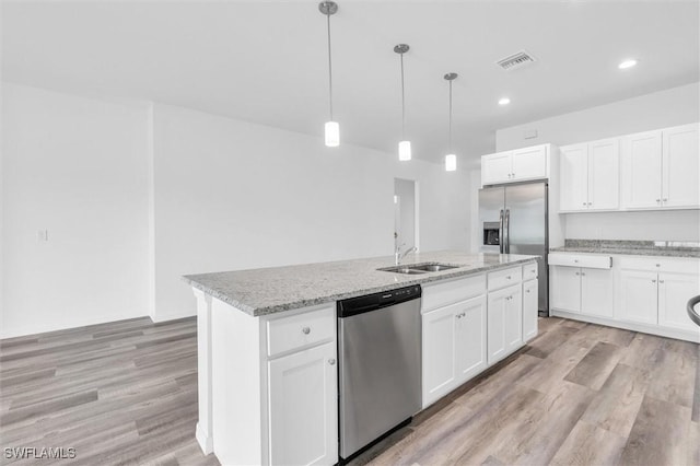 kitchen featuring white cabinets, pendant lighting, an island with sink, and appliances with stainless steel finishes