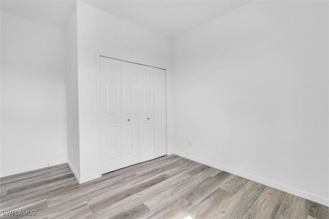 unfurnished bedroom featuring light wood-type flooring and a closet