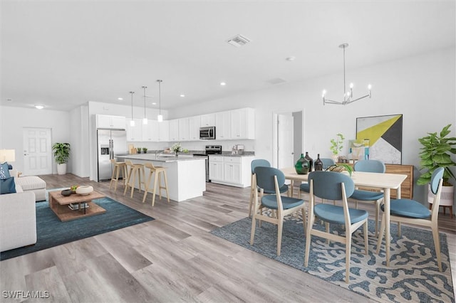 dining space with light wood-type flooring and an inviting chandelier