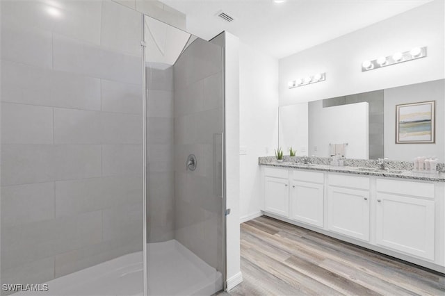 bathroom with tiled shower, hardwood / wood-style floors, and vanity