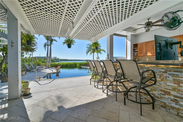 view of patio / terrace featuring ceiling fan, a water view, and exterior bar