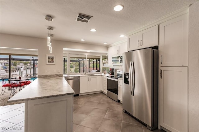 kitchen with sink, white cabinetry, kitchen peninsula, hanging light fixtures, and appliances with stainless steel finishes