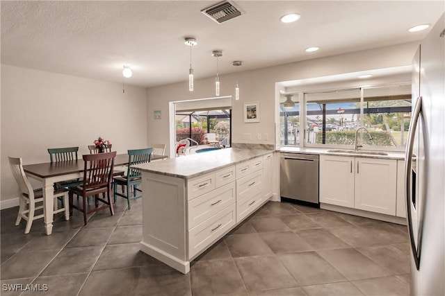 kitchen featuring stainless steel appliances, sink, white cabinets, kitchen peninsula, and pendant lighting