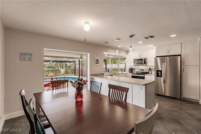 dining area featuring a textured ceiling, dark tile patterned floors, and sink