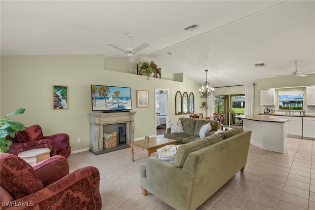 living room featuring lofted ceiling, ceiling fan with notable chandelier, and light tile patterned floors