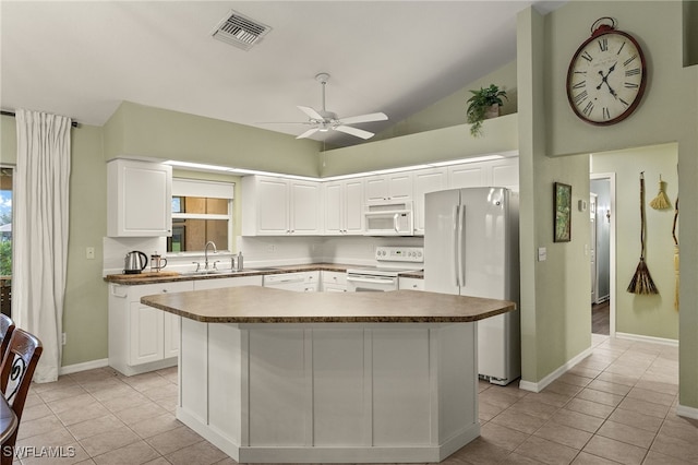 kitchen featuring white cabinetry, a kitchen island, light tile patterned floors, and white appliances