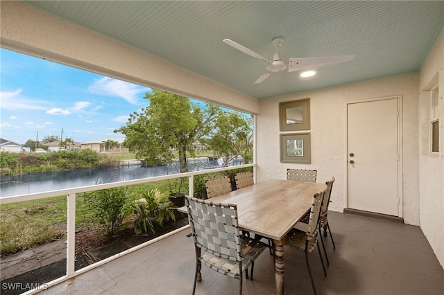 sunroom / solarium featuring ceiling fan and a water view