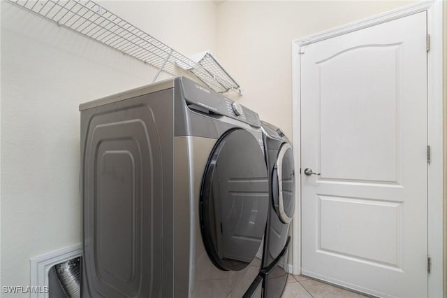 laundry room featuring independent washer and dryer and light tile patterned floors