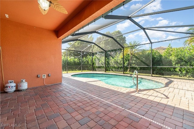 view of pool with glass enclosure, ceiling fan, and a patio